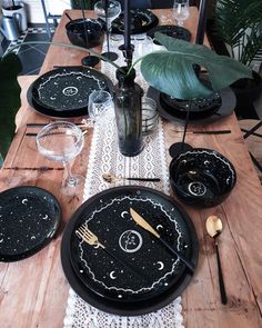 a wooden table topped with black plates covered in stars and moon designs next to a vase filled with flowers