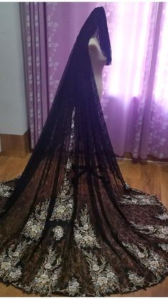 a black and white dress on display in front of a purple wall with curtains behind it