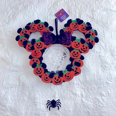 a mickey mouse made out of pumpkins on a white quilted surface with a purple bow