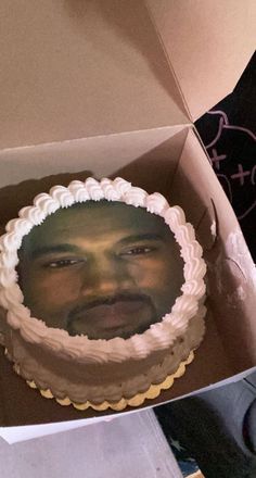 a man's face is shown on top of a cake in a box