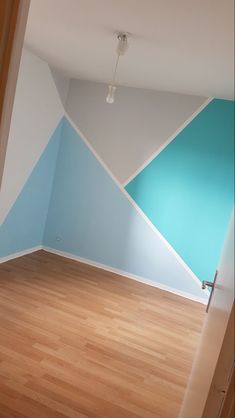 an empty room with blue and white paint on the walls, wood floors and hard wood flooring