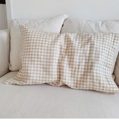 a white couch with a brown and white checkered pillow on it's back