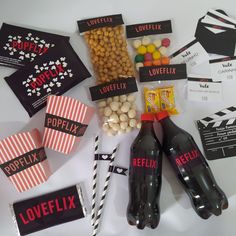 the contents of a movie themed party laid out on a white table with black and red striped paper