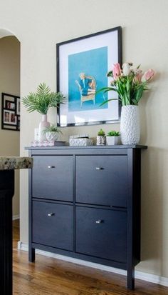 a black dresser with flowers and pictures on the wall