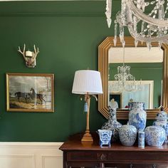 a table with vases, lamps and paintings on the wall