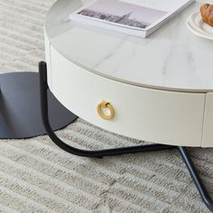 a white table with a black metal base and a book on it's side