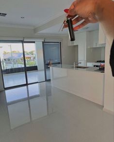 a person holding a remote control in their hand near a kitchen and living room with sliding glass doors