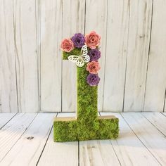 a moss covered letter with flowers in the shape of a number one on a white wooden background