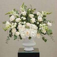 a white vase filled with lots of white flowers