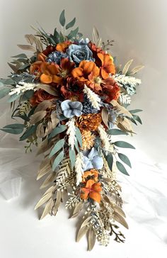 a bridal bouquet with orange, blue and white flowers is on a white surface