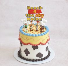 a birthday cake with toy figures on top and the words reach for the sky written above it