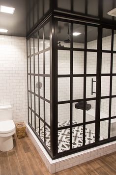 a white toilet sitting in a bathroom next to a shower stall with black and white tiles