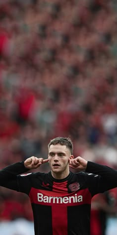 a man holding his hands to his ears while standing on a soccer field