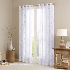 a white curtain hanging on the side of a window next to a vase with flowers