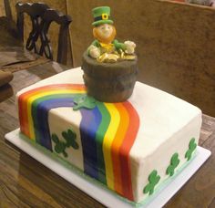 a rainbow cake with a lepreti pot on top and shamrocks in the middle