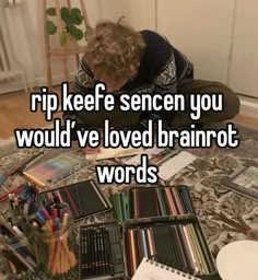 a child is sitting on the floor with books and pencils in front of him