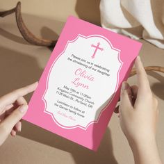 a person holding up a pink and white card with a cross on the front that reads,