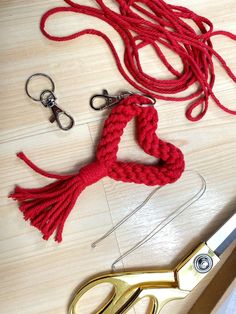 a pair of scissors next to a red rope and some other items on a table