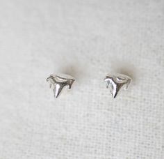 These earrings are cast from a tiny, found kitten tooth. The abstract, triangular shape evokes a mountain range. NATURAL HISTORY Felis catus Kittens first set of teeth, often referred to as milk teeth, come in when kittens are between three and eight weeks old. Cats have 26 milk teeth and 30 permanent teeth - which start to come in when cats are around three months old and replace the first set of teeth over the next few months. Archaeologists have dated cats' domestication back to around 7500 BCE. Through domestication cats' anatomy and behavior has only changed in small ways and they are still adept at surviving in the wild. METAPHOR Persistent wildness, play, the sweet thrum of a purr. MATERIALS + DETAILS stud is approximately .2 inches | 5 mm across recycled sterling silver comes with Cats Anatomy, Milk Teeth, Surviving In The Wild, Old Cats, Mountain Range, Recycled Sterling Silver, Natural History, Kittens, Jewelry Earrings