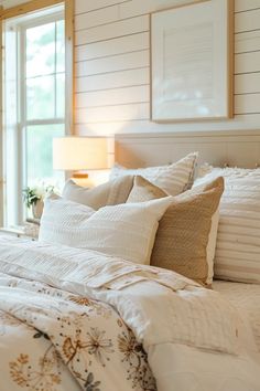 a bed with white sheets and pillows next to a window in a room that has wood paneling on the walls