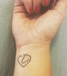 a woman's wrist with a small heart tattoo on the left side of her arm