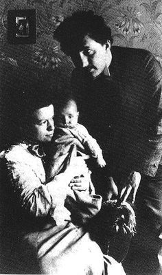 an old black and white photo of a woman holding a baby