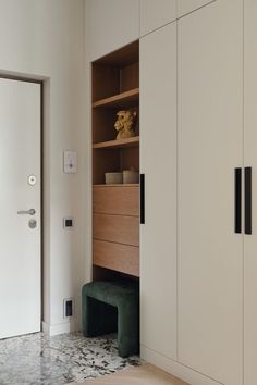 a white closet with wooden shelves and drawers next to a green bench in front of it