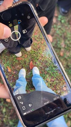 someone holding up their cell phone to take a selfie with his feet on the ground