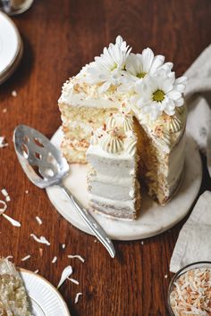 a piece of cake with white frosting and daisies on top is cut into pieces