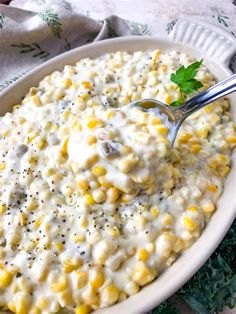 a white bowl filled with creamed corn and garnished with parsley