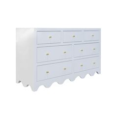 a white dresser with scalloped drawers and gold handles