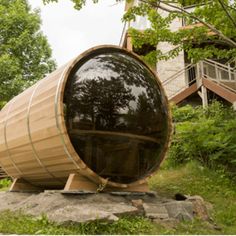 a large wooden barrel sitting on top of a lush green field next to a building