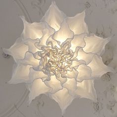 a white flower shaped light hanging from the ceiling in a room with marble walls and flooring