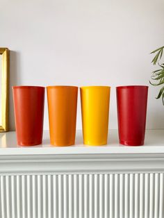 three different colored cups sitting on top of a white mantle