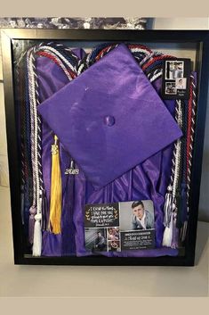 a purple graduation cap and tassels in a shadow box with pictures on it