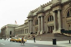 people are walking down the street in front of an old building with columns and pillars