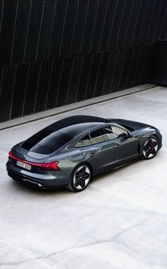 a grey car parked in front of a building with black walls and concrete flooring