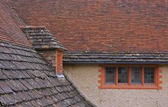 an old brick building with two windows and tiled roofs