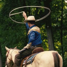 a man riding on the back of a horse holding a lasso above his head