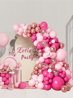 pink and gold balloons are on display in front of a white table with a sign that says let's party