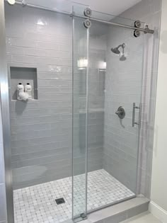 a walk in shower sitting next to a white tiled wall and floor with two faucets on each side