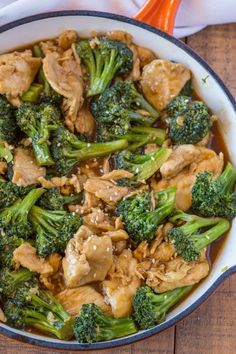 chicken and broccoli stir fry in a skillet on a wooden table top