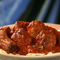 a white bowl filled with meat and pasta on top of a blue cloth covered table