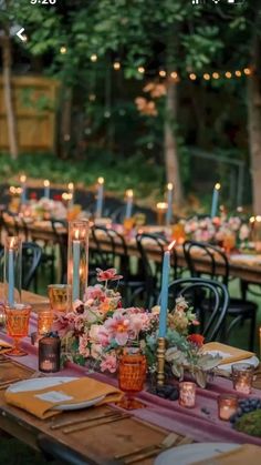 a long table with candles and flowers on it is set up for an outdoor dinner