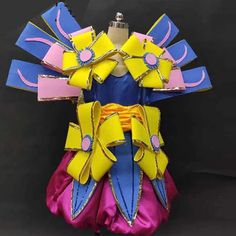 a dress made out of paper with yellow, pink and blue ribbons on the back