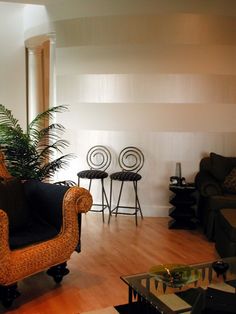 a living room filled with furniture next to a tall plant on top of a hard wood floor