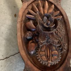 an ornate carved wooden plaque with flowers and leaves on it's face, hanging from a wall