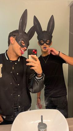 two people wearing bunny ears taking a selfie in front of a mirror with their cell phone