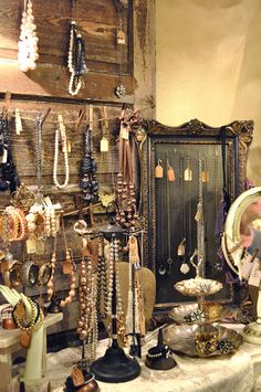 an old fashion store with lots of necklaces and jewelry hanging on the wall next to a mirror