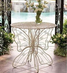 a white table with flowers on it in front of a swimming pool and gazebo